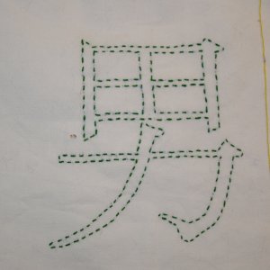 Beispiel f&uuml;r einfachen Vorstich: Das Kanji f&uuml;r Mann in dunkelgr&uuml;nem Vorstich. Vorlage in Pinselschrift.