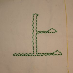 Beispiel f&uuml;r durchzogenen Vorstich: Das Kanji f&uuml;r Oben in hellgr&uuml;nem Vorstich, umschlungen in Dunkelgr&uuml;n. Vorlage in Pinselschrift.